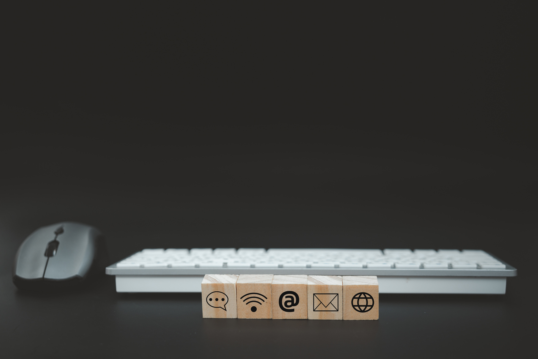 Online business communication symbols contact us or e-mail address marketing concept on wooden cubes with computer keyboard background.